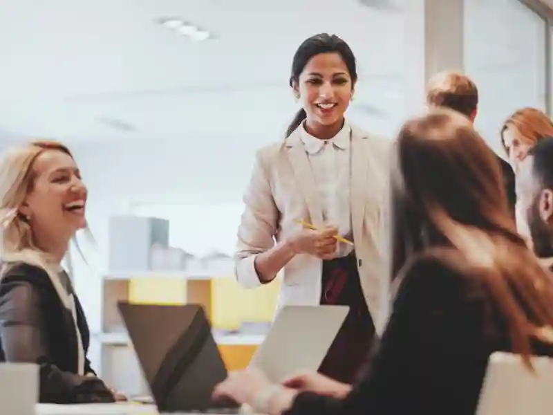 Three women and a man at a conference table smiling and talking