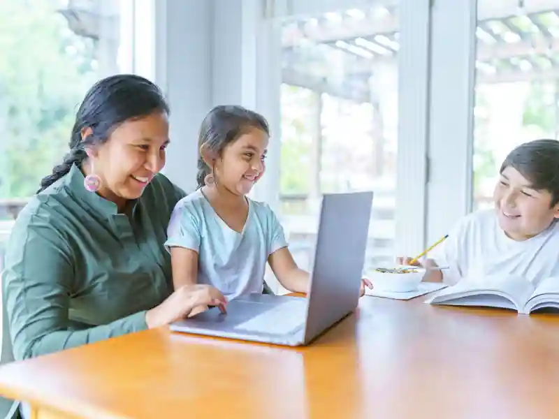 Indigenous family sitting at the dining table with a laptop