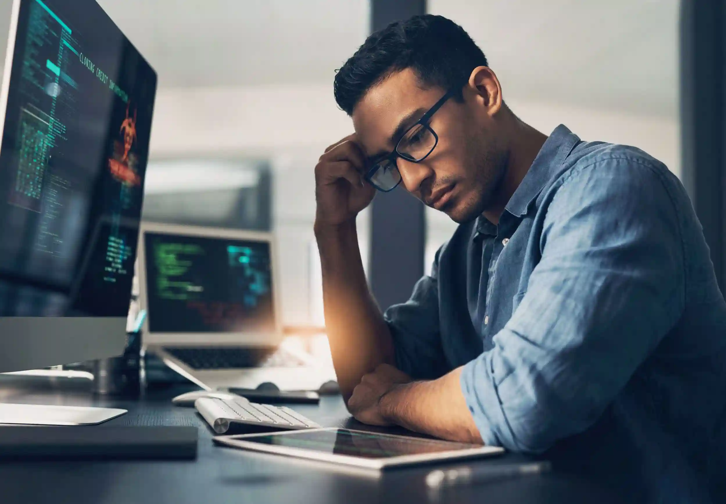 Frustrated man sitting at his desk after a cybersecurity breach in the office. 