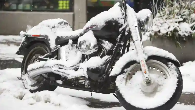 A motorcycle blanketed in snow, showcasing a serene winter scene with white snowflakes covering its surface.