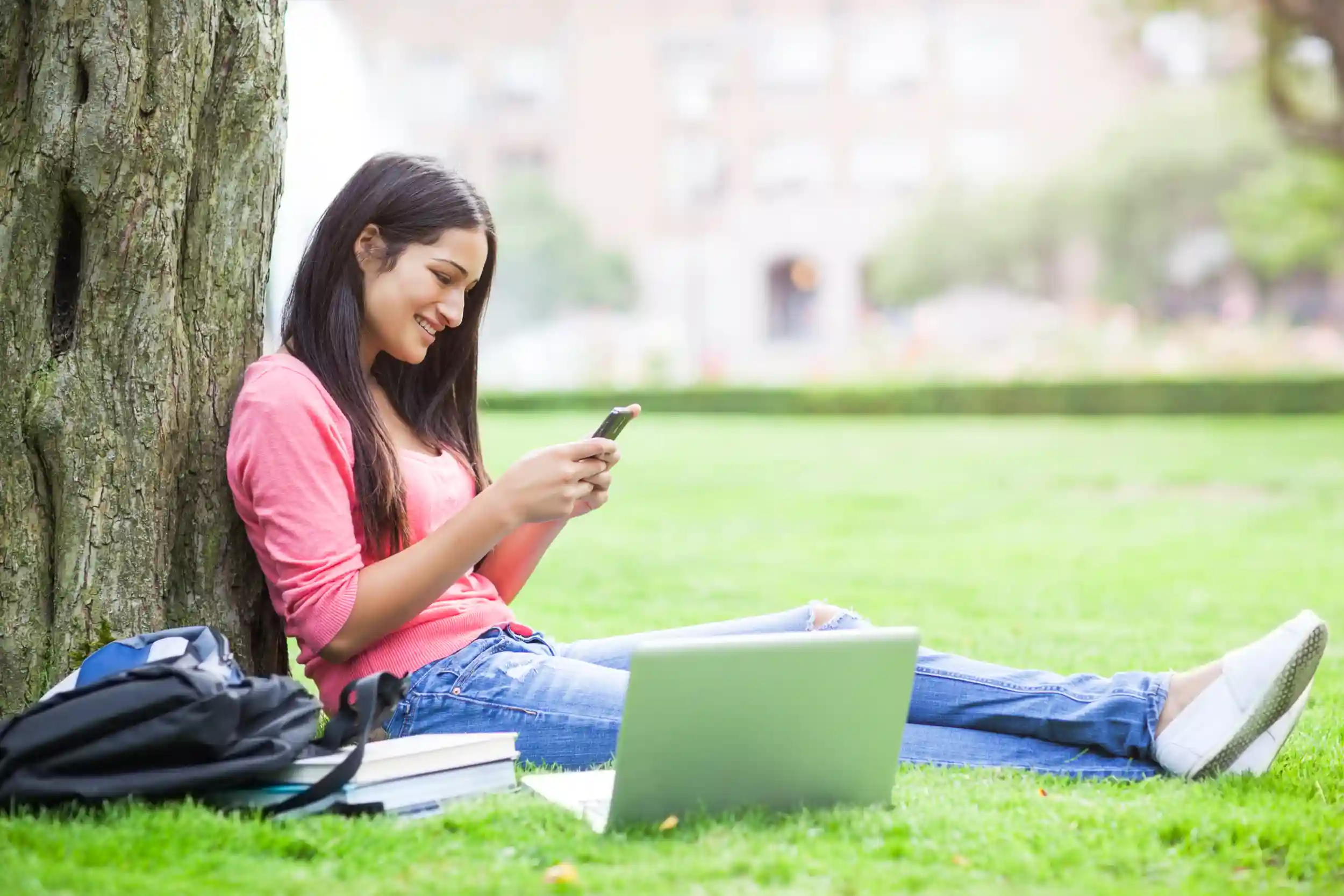 College student sitting against a tree in the quad.