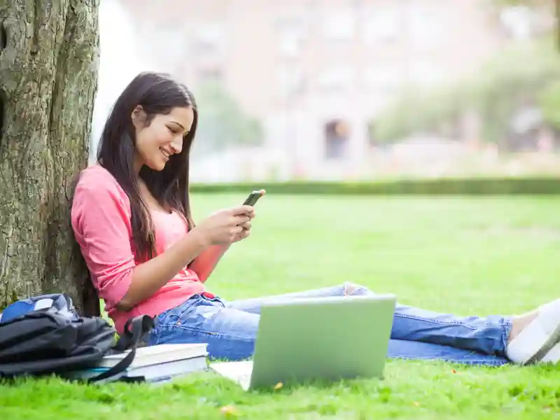 College student sitting against a tree in the quad.