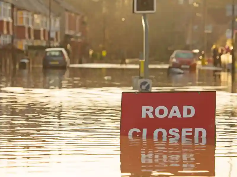 A street flooded with cars stuck and a "Road Closed" sign.