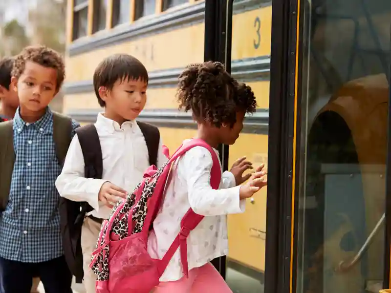 Children getting on a yellow school bus.