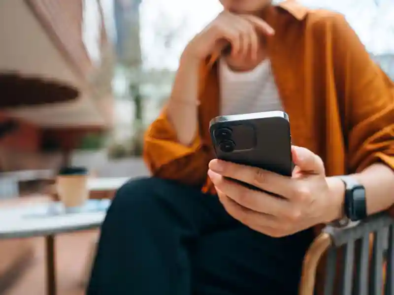 Woman holding phone sitting outside a coffee shop