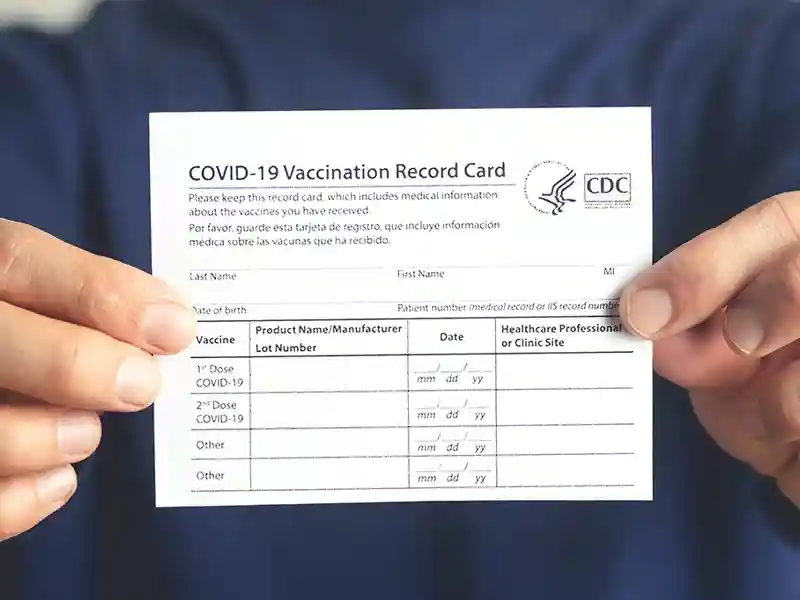 A close up of a person holding a COVID-19 vaccination card.