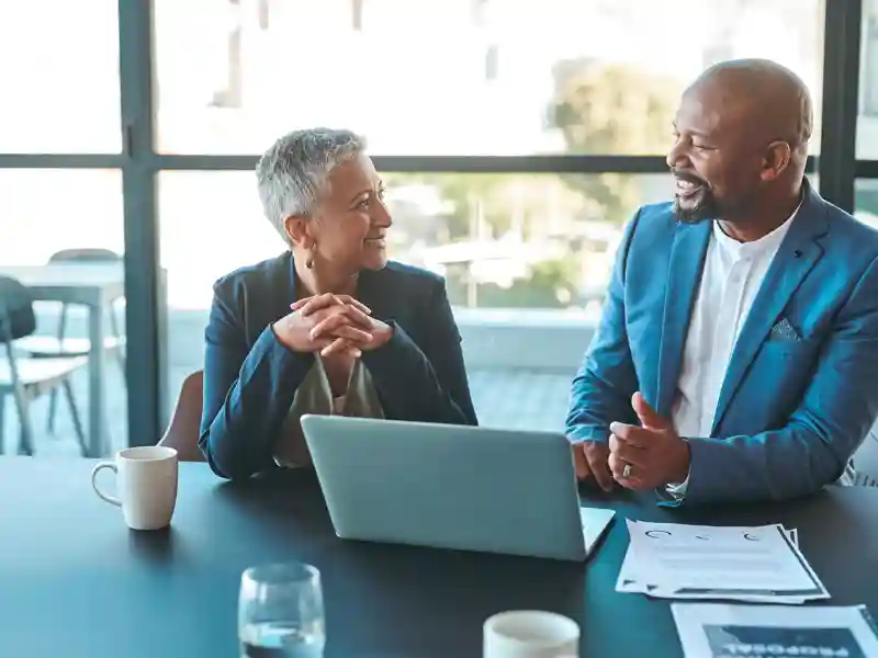 Employees smiling around a laptop.
