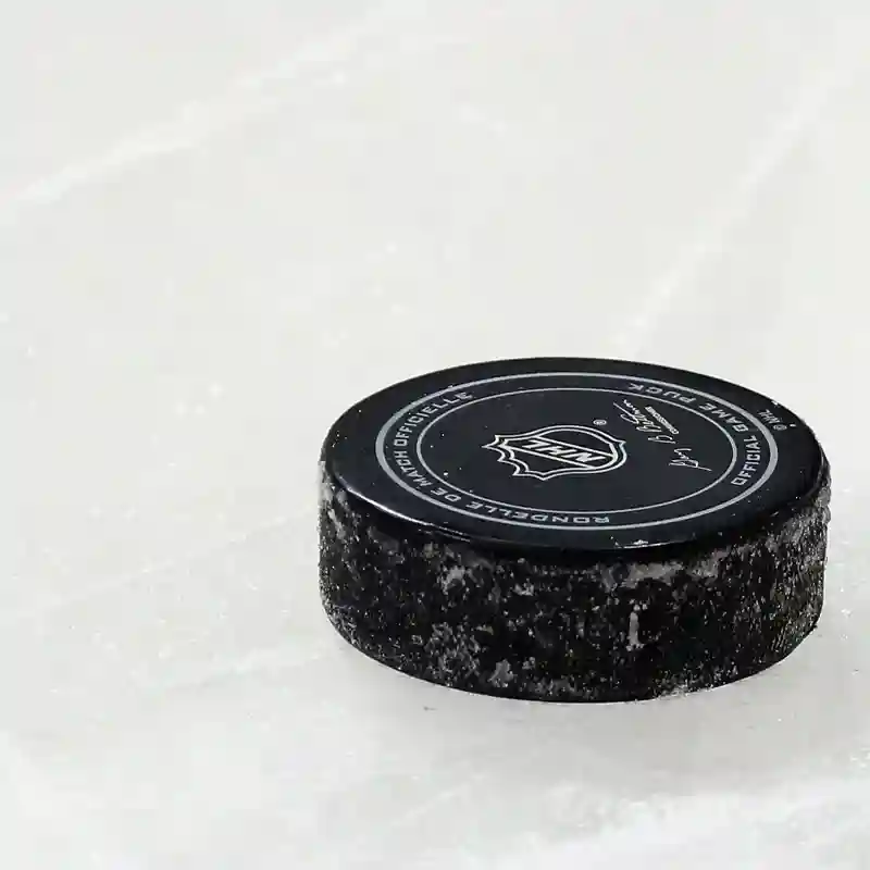 Close up of a hockey puck on the ice featuring the NHL logo