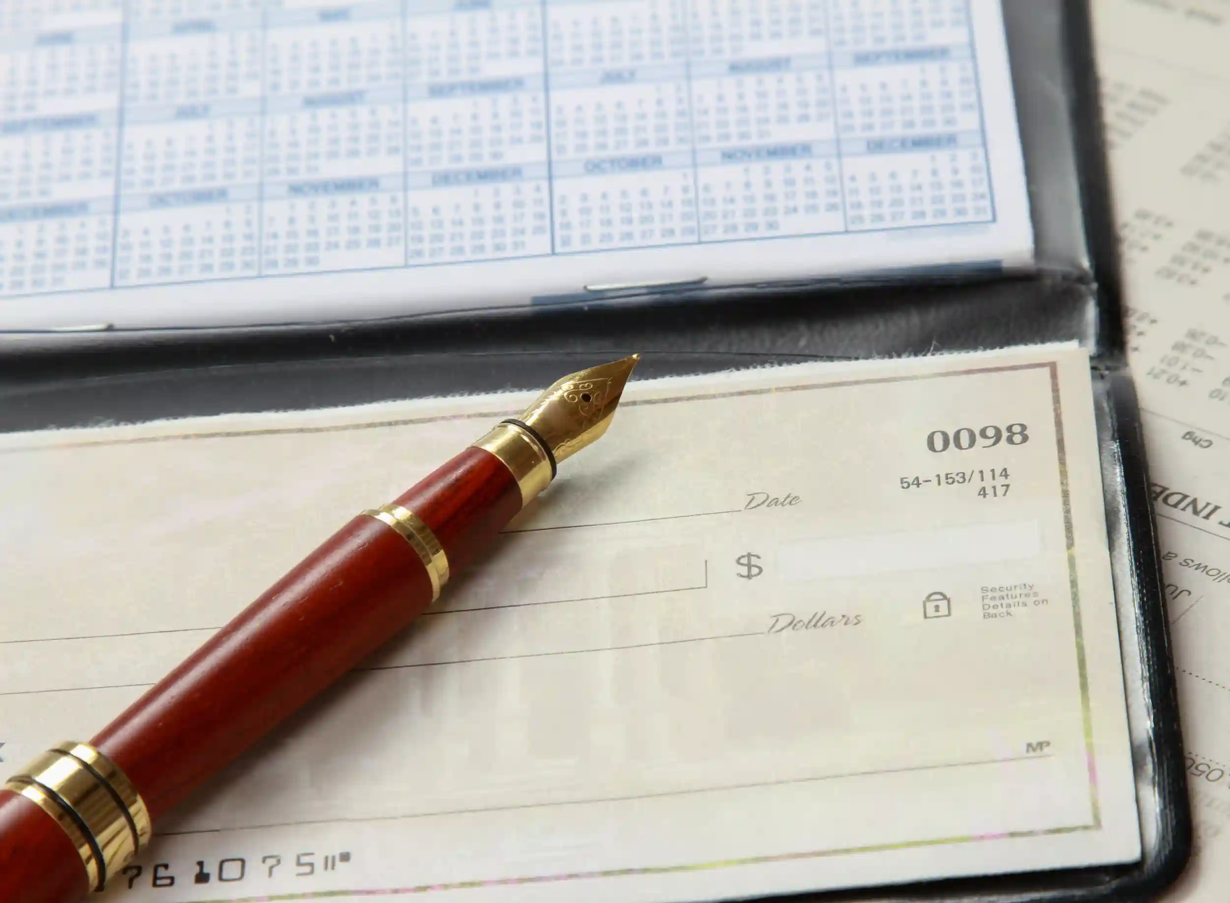 A red pen on top of a checkbook.