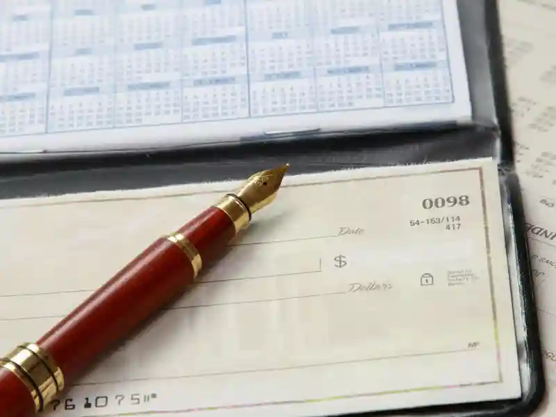 A red pen on top of a checkbook.