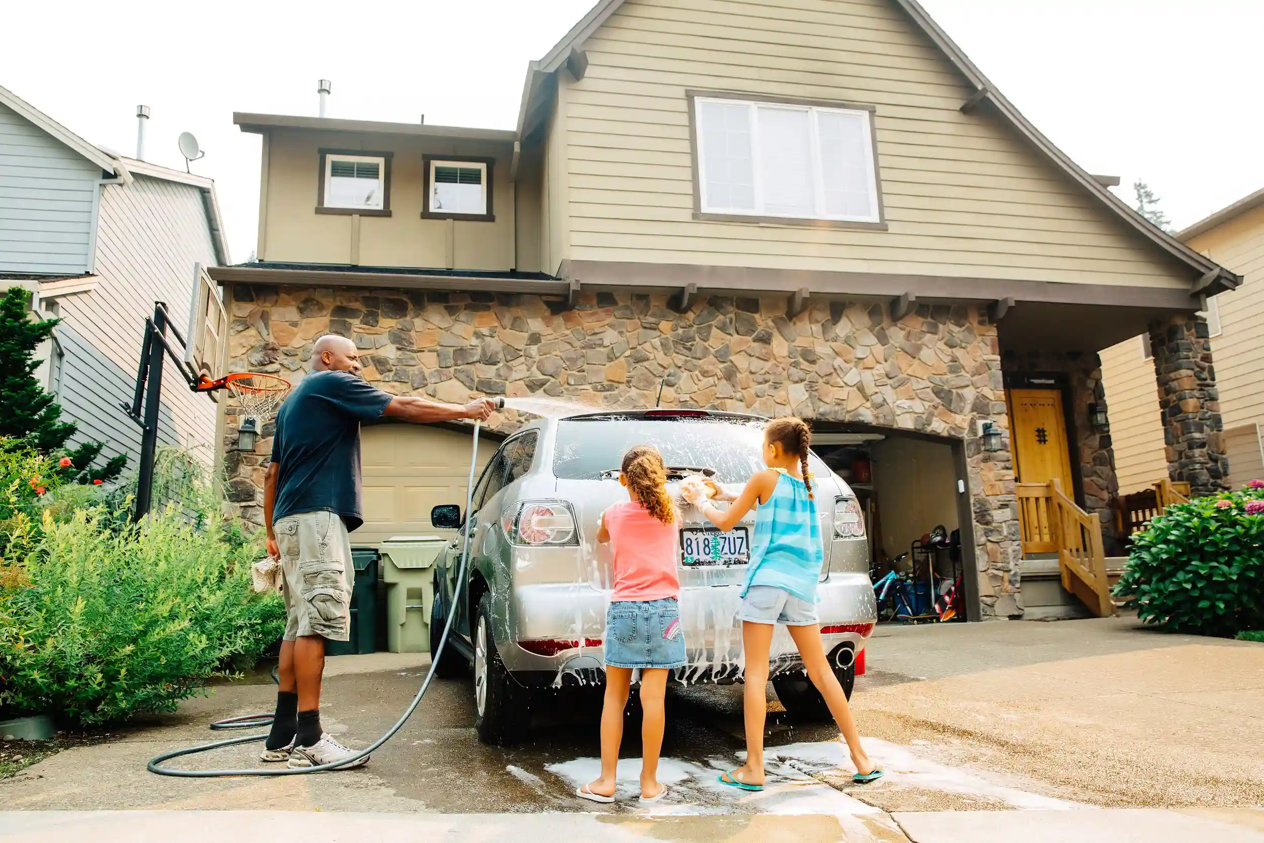 Father and daughters washing car.