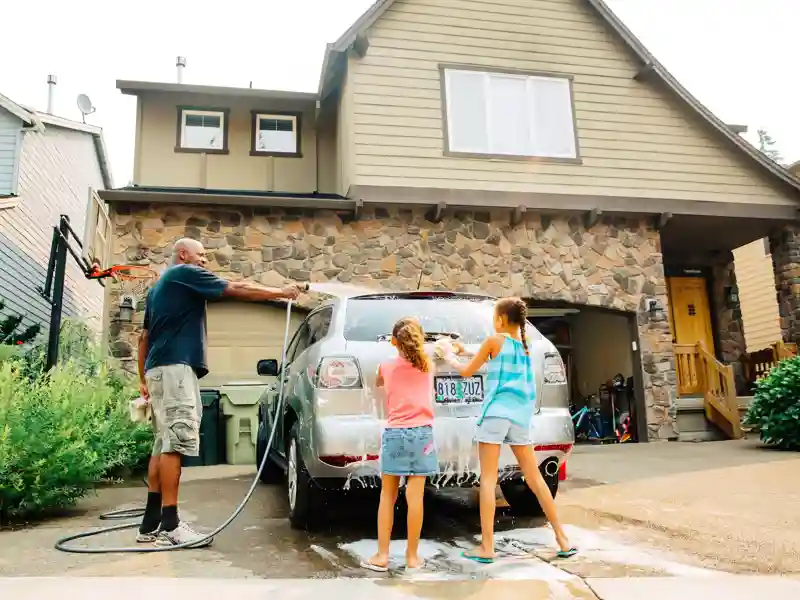Father and daughters washing car.