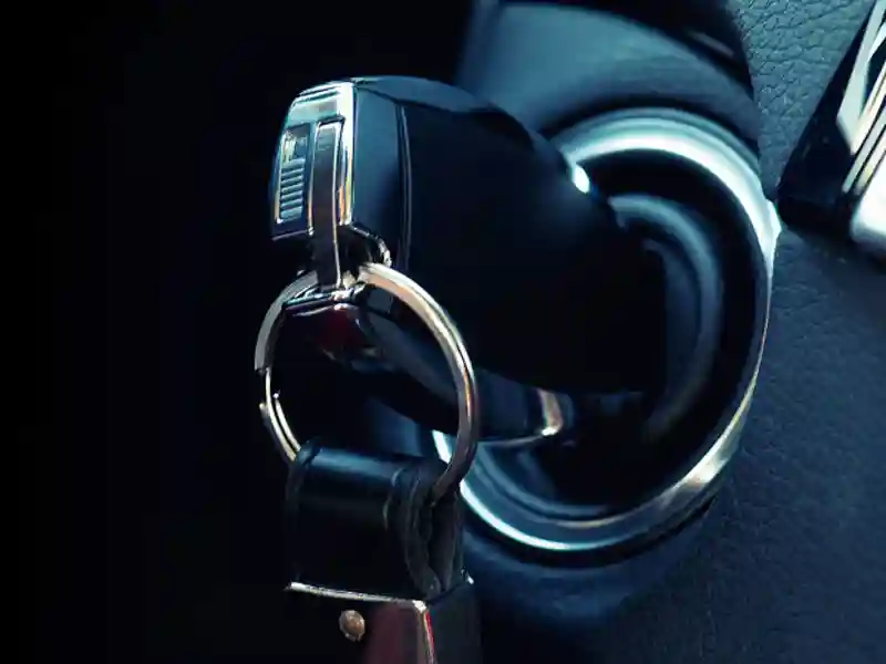A key fob, with keychain, inserted into the ignition of a car.