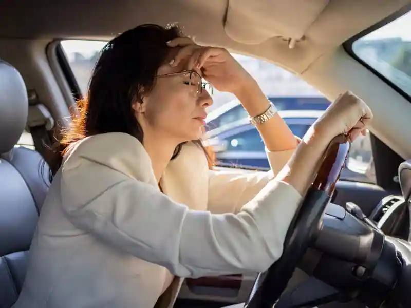 Woman holding her head frustrated in a car.