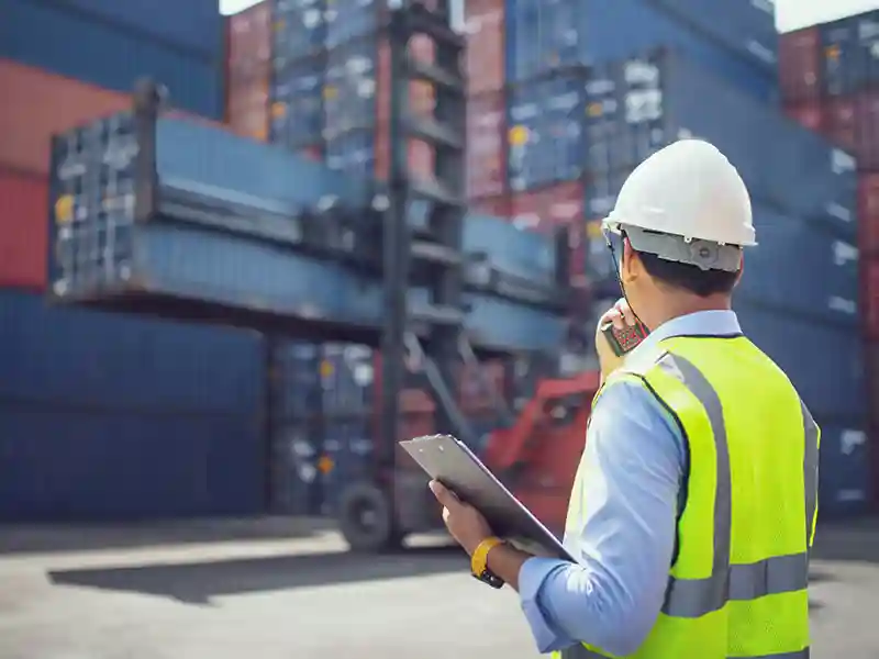 A dock worker carries a clipboard